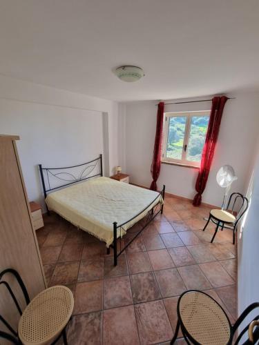 a bedroom with a bed and two chairs and a window at I giardini del castello in Mandatoriccio Marina