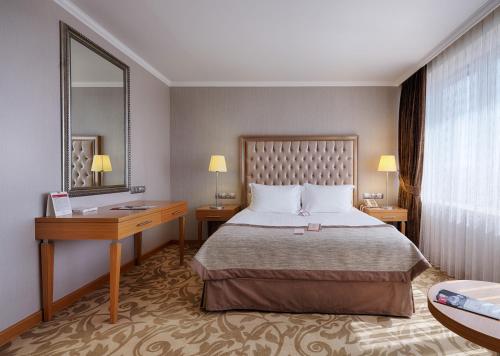 a bedroom with a bed and a desk and a mirror at Ramada Plaza By Wyndham Kahramanmaras in Kahramanmaraş