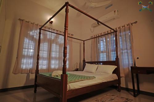 a bedroom with a four poster bed with windows at Serenity Villa and Treehouse in Palakkad