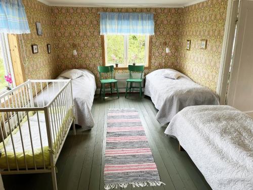 um quarto com 2 camas individuais e um berço em Cozy red cottage in the countryside outside Vimmerby em Gullringen