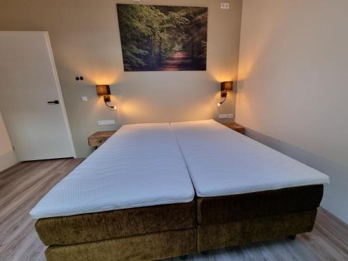 een groot bed in een kamer met een schilderij aan de muur bij DW Castricum in Castricum