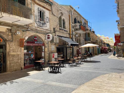 une rue vide avec des tables, des chaises et des bâtiments dans l'établissement GoodHouse 403 - Pretty Flat near Mamilla, à Jérusalem