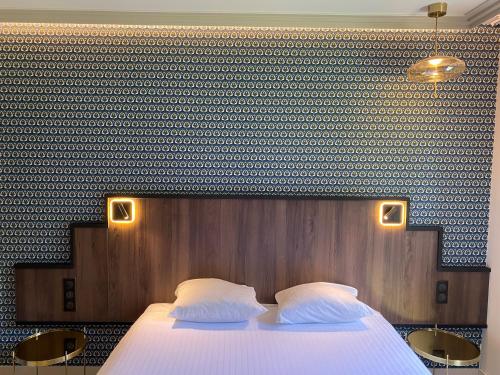 a bedroom with a large bed with two white pillows at Hôtel Lancelot & Spa - Domaine du Roi Arthur in Ploërmel