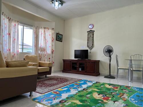 a living room with a couch and a tv and a rug at D'Puncak Arabella Muslim Homestay in Cameron Highlands
