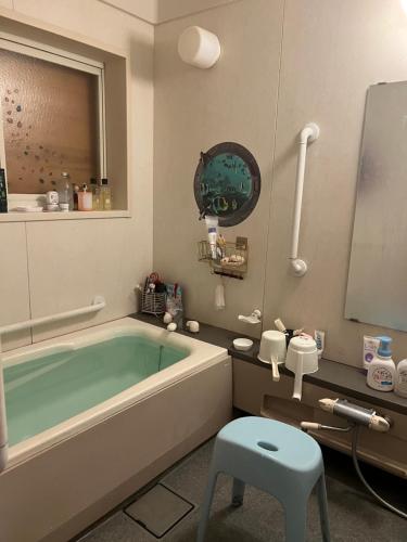 uma casa de banho com banheira e um banco em 天女座エンタティメントゲストハウス em Kumano