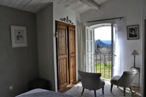 een slaapkamer met een bed en een groot raam bij Le Mas En Provence in Entrechaux