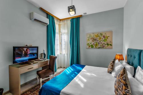 Cette chambre comprend un lit, un bureau et une télévision. dans l'établissement Lacasa Nizami Street, à Baku