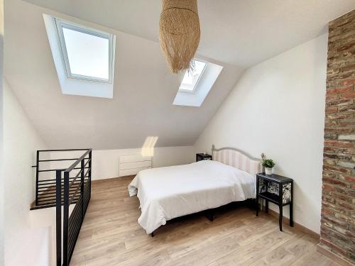 a attic bedroom with a bed and two windows at Au Duplex indus/chic de Breteuil in Breteuil