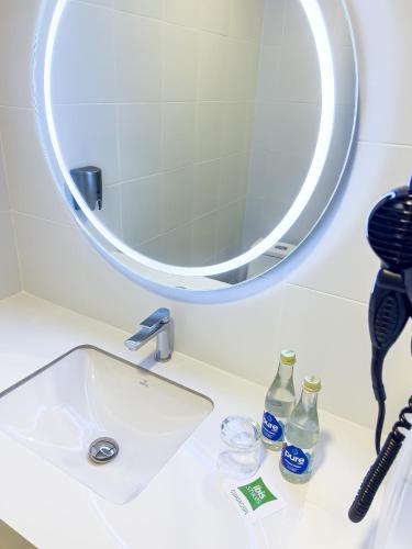 a bathroom sink with a mirror and bottles on it at Ibis Styles El Malecon Guayaquil in Guayaquil