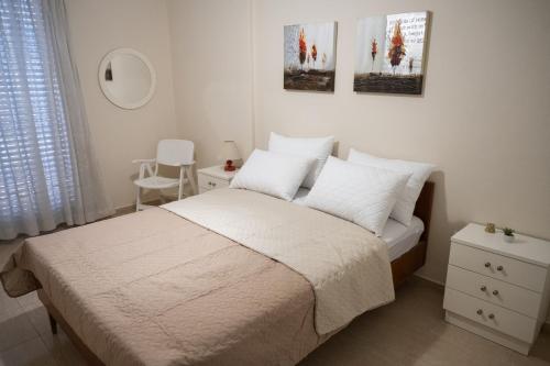 a bedroom with a bed with white sheets and pillows at KLEIO in Nea Moudania