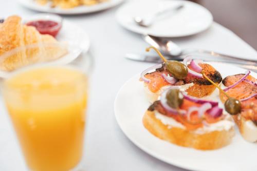 a table with a plate of food and a glass of orange juice at Hotel Lindauer Hof in Lindau