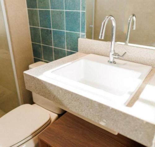 a bathroom with a white sink and a toilet at Suite - Aqualand Suites in Salinópolis