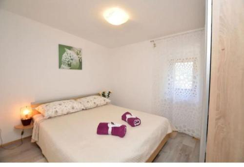 een slaapkamer met een groot wit bed met paarse kussens erop bij Family Green apartman Carlo in Kršan