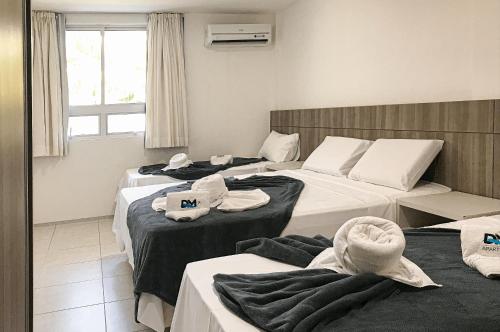 a hotel room with three beds with towels on them at Paraíso das Dunas Pé na Areia 2 Suítes 6 Pessoas in Aquiraz
