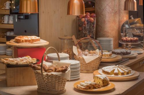 a table with plates and baskets of bread and pastries at Bellavista Relax Hotel in Levico Terme