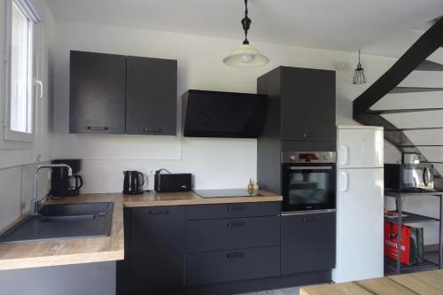 - une cuisine avec des armoires noires et un réfrigérateur blanc dans l'établissement La Maison d'Alphonse, à Avignon