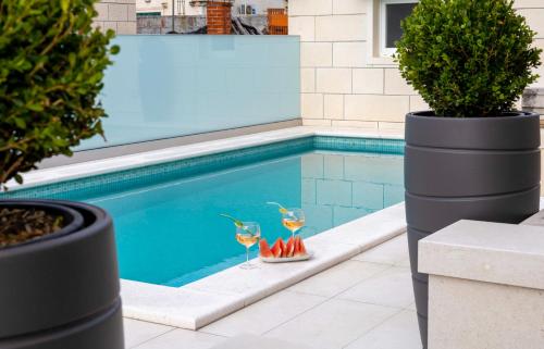 a pool with two glasses of wine and a tray of cocktails at Insula Apartment with Private Pool in Pučišća
