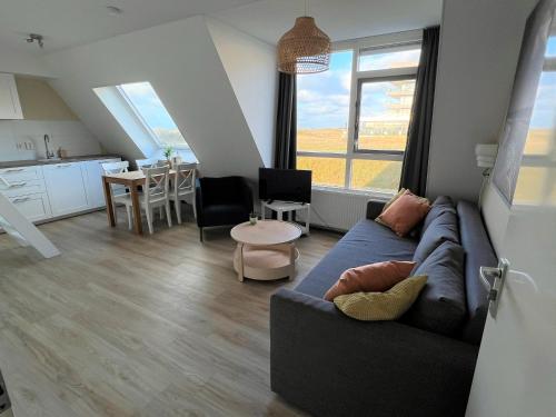 a living room with a blue couch and a kitchen at Moana in Egmond aan Zee