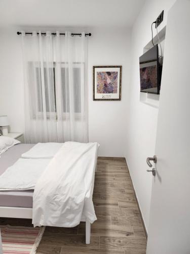 a white bedroom with a bed and a window at H&D Apartment in Sumartin