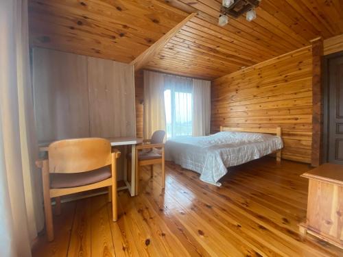 a bedroom with a bed and a desk in a wooden room at Pulmo rest house in Pulʼmo
