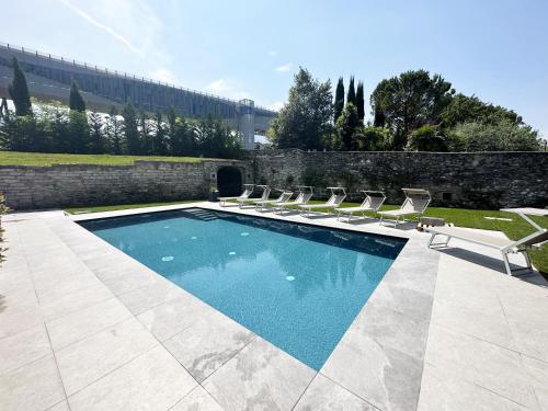 a swimming pool with lounge chairs next to a wall at Residence Zangirolami - Luxury Garden and Balcony Apartments in Riva del Garda