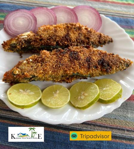 two pieces of fish on a plate with lime slices at Kannur west beach homestay in Kannur