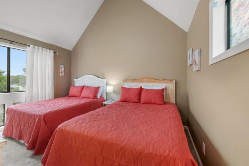 two beds in a bedroom with red sheets and a window at Arcadian Dunes 312 in Myrtle Beach
