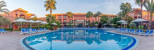 a pool with chairs and umbrellas in front of a hotel at Labranda Targa Aqua Parc in Marrakech