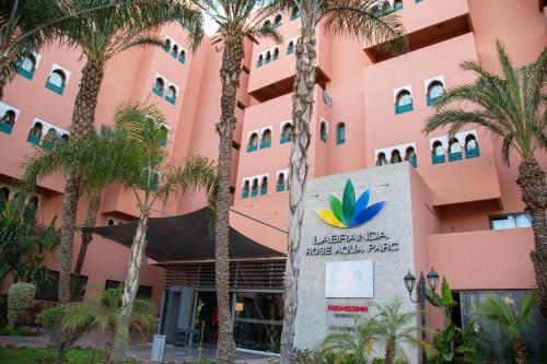 a pink building with palm trees in front of it at Labranda Rose Aqua Parc in Marrakech