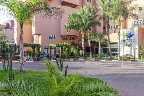 a large pink building with palm trees in front of it at Labranda Rose Aqua Parc in Marrakech