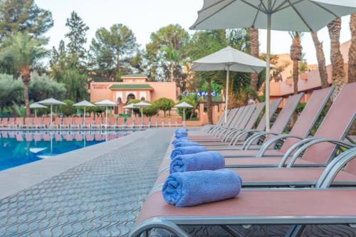 a row of chairs with blue pillows on them next to a pool at Rose Aqua Park Hotel in Marrakesh