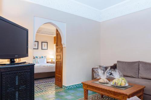 a living room with a couch and a tv at Rose Aqua Park Hotel in Marrakesh