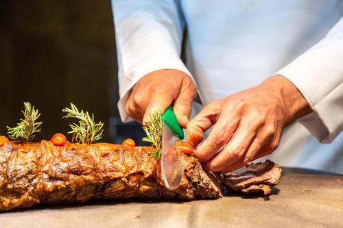a man cutting a piece of meat with a knife at Rose Aqua Park Hotel in Marrakesh
