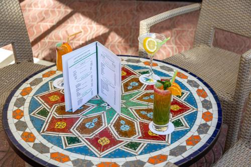 a table with a book and two drinks on it at Rose Aqua Park Hotel in Marrakesh