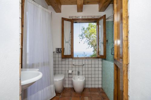 La salle de bains est pourvue d'un lavabo, de toilettes et d'une fenêtre. dans l'établissement Cottage Casale relax e tranquillità, à Gioiosa Marea