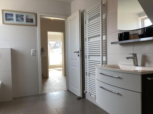 a white bathroom with a sink and a door at Kellenhusen - Ferienhaus Gabi in Kellenhusen