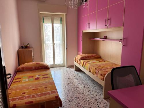 Pokój z 2 łóżkami i różowymi szafkami w obiekcie Casa Vacanza dai Compari w mieście Ali Terme