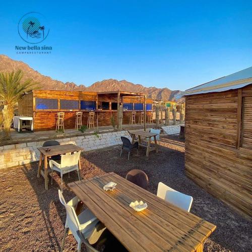 a patio with a wooden table and chairs and a building at New Bella Sina Camp in Nuweiba