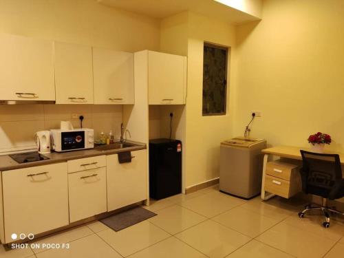 a kitchen with white cabinets and a desk and a refrigerator at CQ3311- SELF CHECK-IN- WI-FI- NETFLIX- PARKING-BALCONY - CYBERJAYa , 2018 in Cyberjaya
