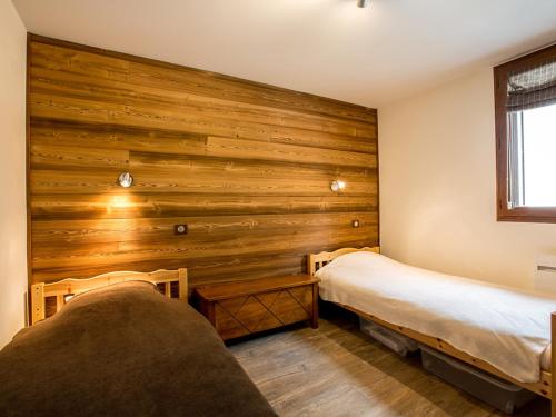 - une chambre avec 2 lits et un mur en bois dans l'établissement Appartement 2 chambres avec garage, centre village, proche pistes, WiFi - FR-1-437-77, à La Clusaz