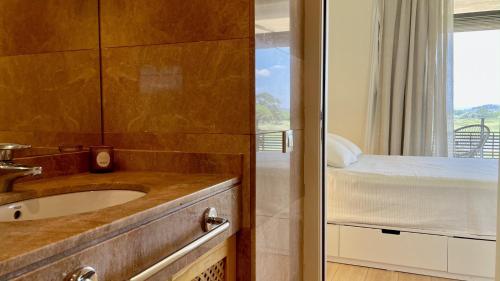 uma casa de banho com um lavatório e uma cama com uma janela em Empordà Golf 4 1-3 em Gualta