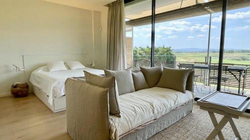 a bedroom with a bed and a couch in front of a window at Empordà Golf 4 1-3 in Gualta