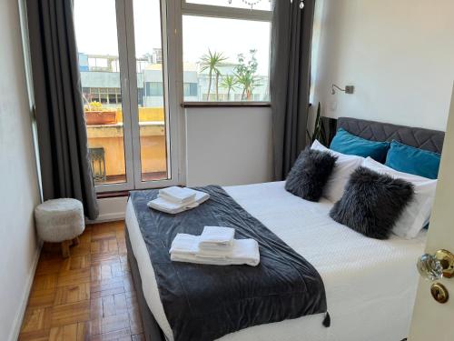 1 dormitorio con 1 cama con toallas y ventana en Apartamento Trindade en Oporto