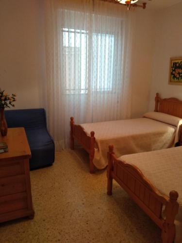 um quarto com 2 camas, uma cadeira e uma janela em Margaritas em Alcossebre