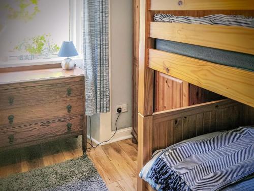 a bedroom with a wooden bunk bed and a window at Firwood Apartment in Kilmun