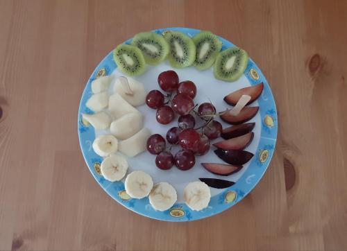 a blue plate of fruit on a wooden table at Paraskevi's Luxury Studios in Parga