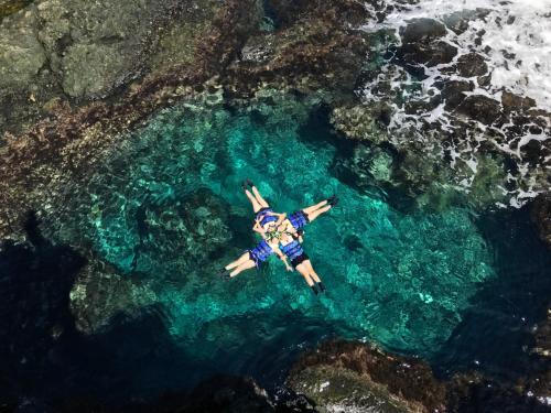a man laying in the water next to the ocean at Green Island Coastal Homestay in Green Island