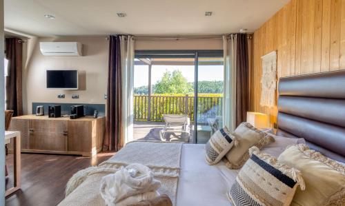 a hotel room with a bed and a balcony at Domaine de Chalvêches Hôtel SPA 4* in Faugères in Rhone-Alpes