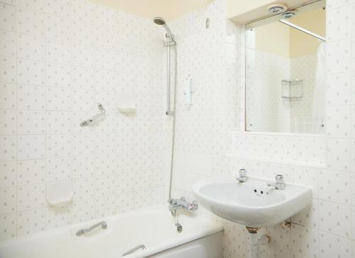 a white bathroom with a sink and a mirror at Bell by Greene King Inns in Thetford