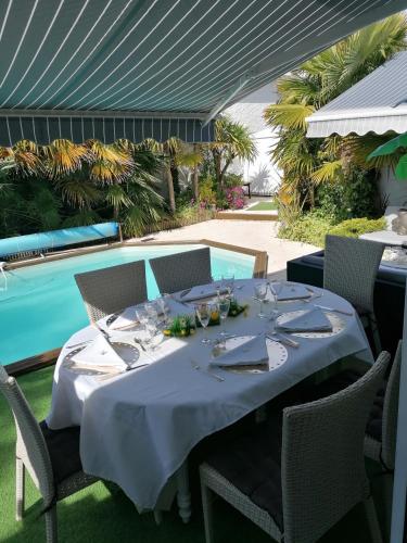 - une table avec des verres à vin à côté de la piscine dans l'établissement maison calme avec piscine palmiers 300m de la plage pornichet centre, à Pornichet